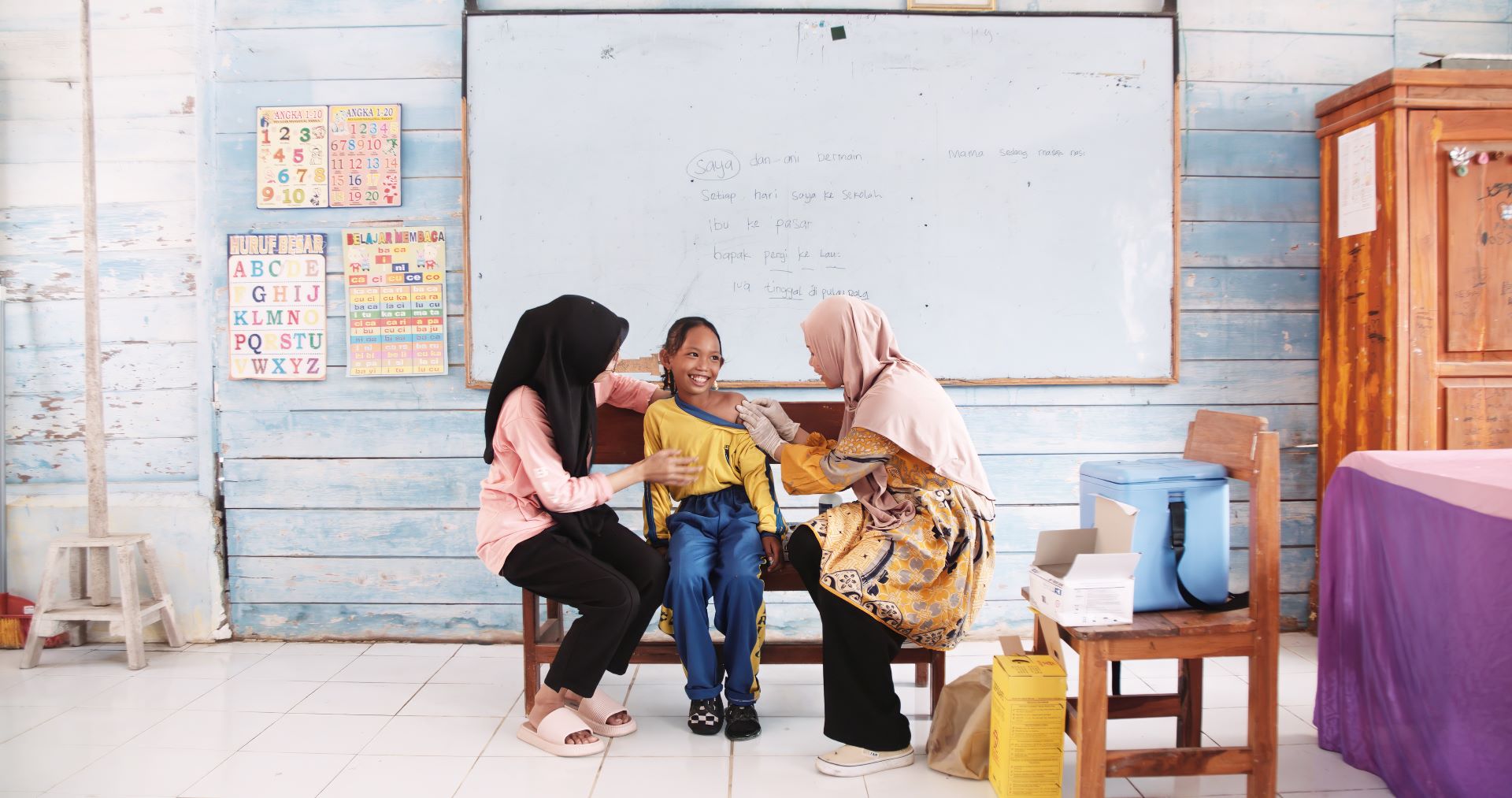 Rahmi (Mimi), a midwife, applies an adhesive bandage to 10-year-old Fitriani, after she receives her vaccination against human papillomavirus (HPV)