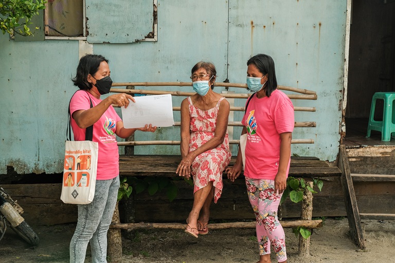 Barangay Health Worker Lorena Ida (left) shares the benefits of COVID-19 vaccines to a senior citizen in Manicani Island, Eastern Samar.